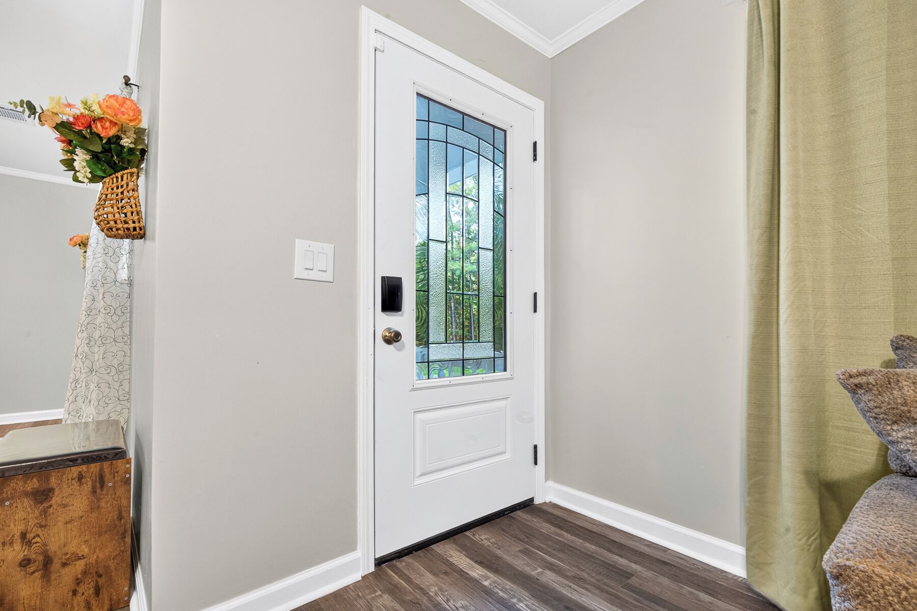 A white door with a glass panel, a wooden floor, and a green curtain.