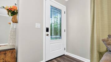 A white door with a glass panel, a wooden floor, and a green curtain.