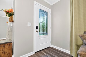 A white door with a glass panel, a wooden floor, and a green curtain. - The Drylog Cottage . Peaceful 3BR Retreat (Kingstree)