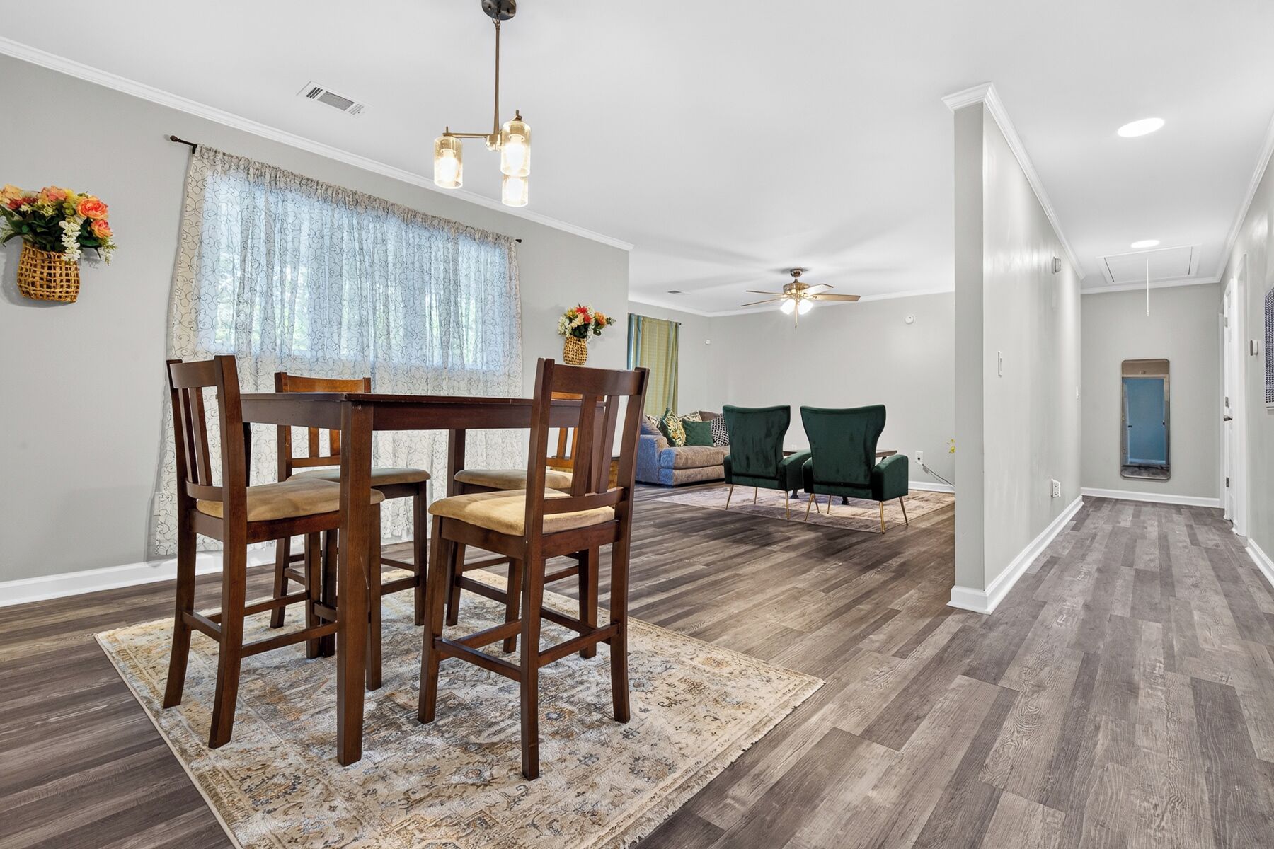 A dining area with a wooden table and chairs, a patterned rug, and a ceiling fan.