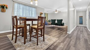 A dining area with a wooden table and chairs, a patterned rug, and a ceiling fan.
