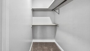 A corner of a room with white walls, a grey carpet, and a black ceiling light fixture.