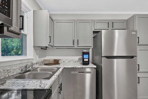 A kitchen with stainless steel appliances, a marble countertop, and white cabinetry.