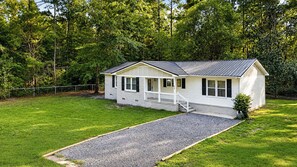 A single-story house with a front porch, a gravel driveway, and a fenced yard. - The Drylog Cottage . Peaceful 3BR Retreat (Kingstree)
