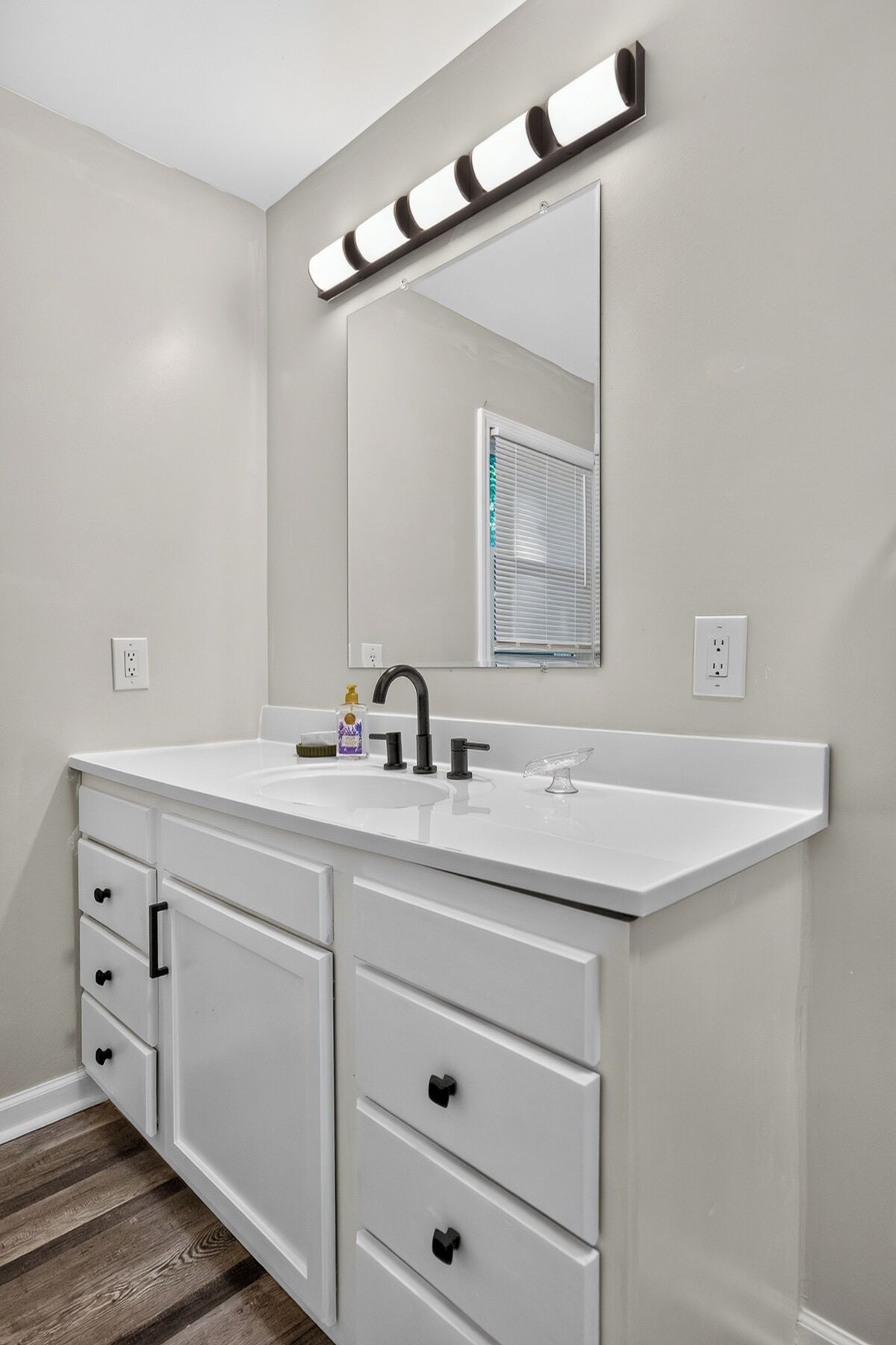 A bathroom with a white vanity, a mirror, and a lighted vanity mirror.