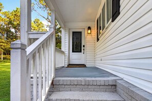 A white house with a front porch, a door, and a small set of steps leading to the entrance.