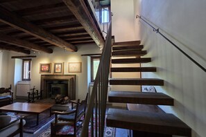 A staircase with wooden steps leading to an upper floor, a fireplace with a mantel, and framed artwork on the wall. - Villa Tufi by MMega (Montone)