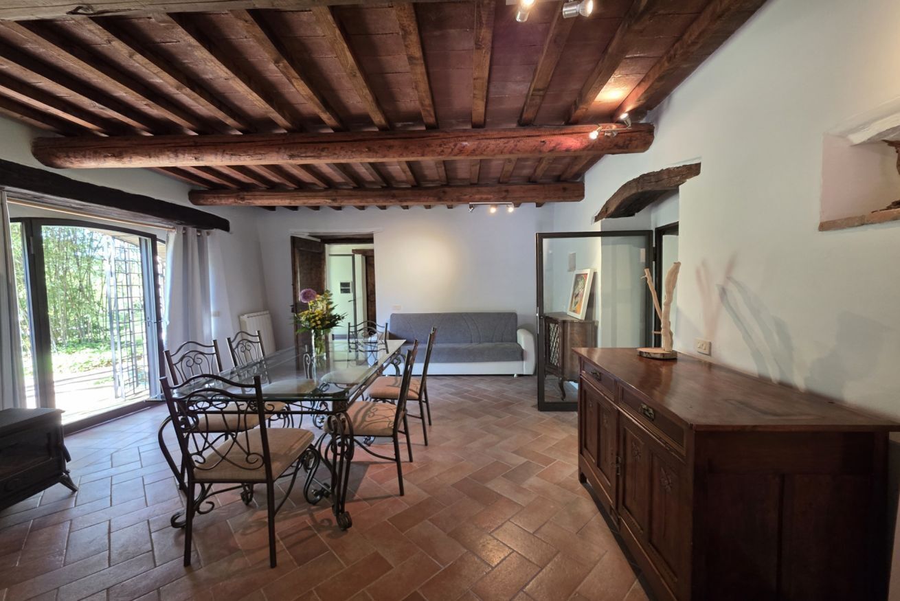A dining area with a wooden ceiling, a glass table, and chairs.