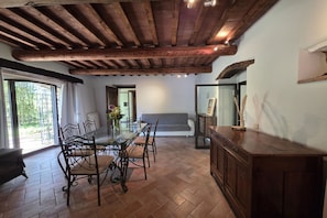 Een eetruimte met een houten plafond, een glazen tafel en stoelen.
