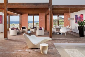 Ein modernes Interieur mit Meerblick, ausgestattet mit zeitgenössischen Möbeln und einer Holzbalkendecke.