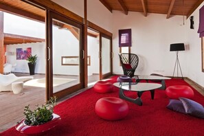 Ein modernes Interieur mit einem roten Teppich, einem schwarzen Sessel und einem Glastisch.