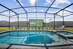 Ein Pool mit einer Aussichtsplattform, umgeben von einem Metallgerüst, eine große Leinwand mit dem NFL-Logo und ein klarer Himmel.