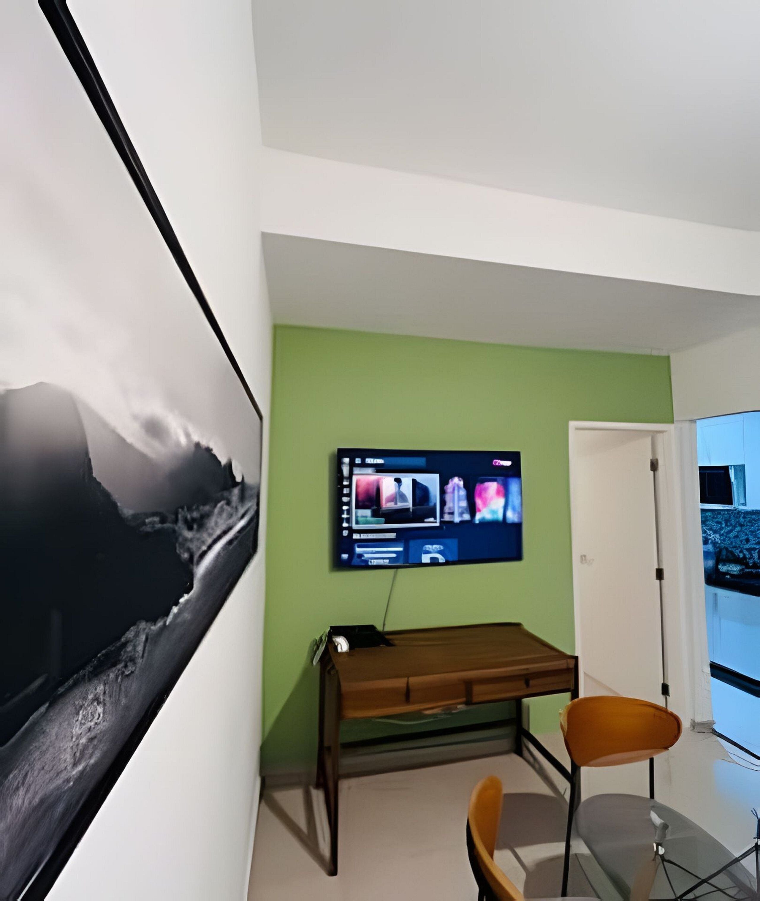 A room with a mounted television, a desk, and a chair.