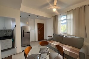 Une cuisine moderne équipée d’un réfrigérateur, d’une table à manger avec des chaises, d’un canapé et d’un ventilateur de plafond.