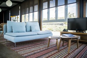 Ein modernes Wohnzimmer mit einem hellblauen Sofa, einem Flachbildfernseher und einem gemusterten Teppich.