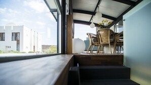 A modern interior with a view of a building outside, a set of stairs, and wicker furniture. - Casas Bioclimáticas Iter La Religa (Granadilla de Abona)