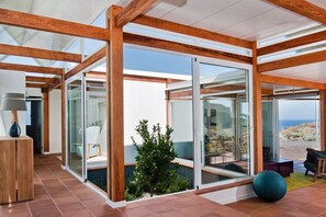 A modern interior with glass doors leading to a balcony, wooden beams, and a small indoor plant. - Casas Bioclimáticas Iter El Escudo (Granadilla de Abona)