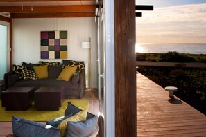 A living room with a sofa and coffee table, a wall art piece, and a view of the sea. - Casas Bioclimáticas Iter El Escudo (Granadilla de Abona)