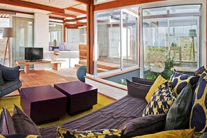 A modern living room with a sofa, a television, and a balcony with a view. - Casas Bioclimáticas Iter El Escudo (Granadilla de Abona)