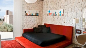Una camera da letto moderna con un divano letto rosso, un'ampia finestra e opere d'arte alle pareti.