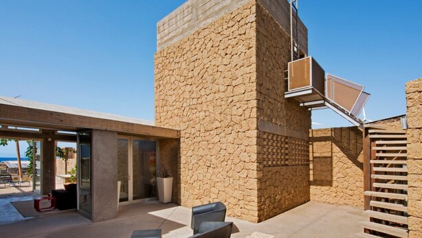 Un edificio moderno con facciata in pietra, area salotto esterna e una scalinata.