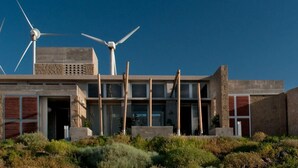 Un edificio moderno con diverse turbine eoliche, un tetto piano e un paesaggio desertico.
