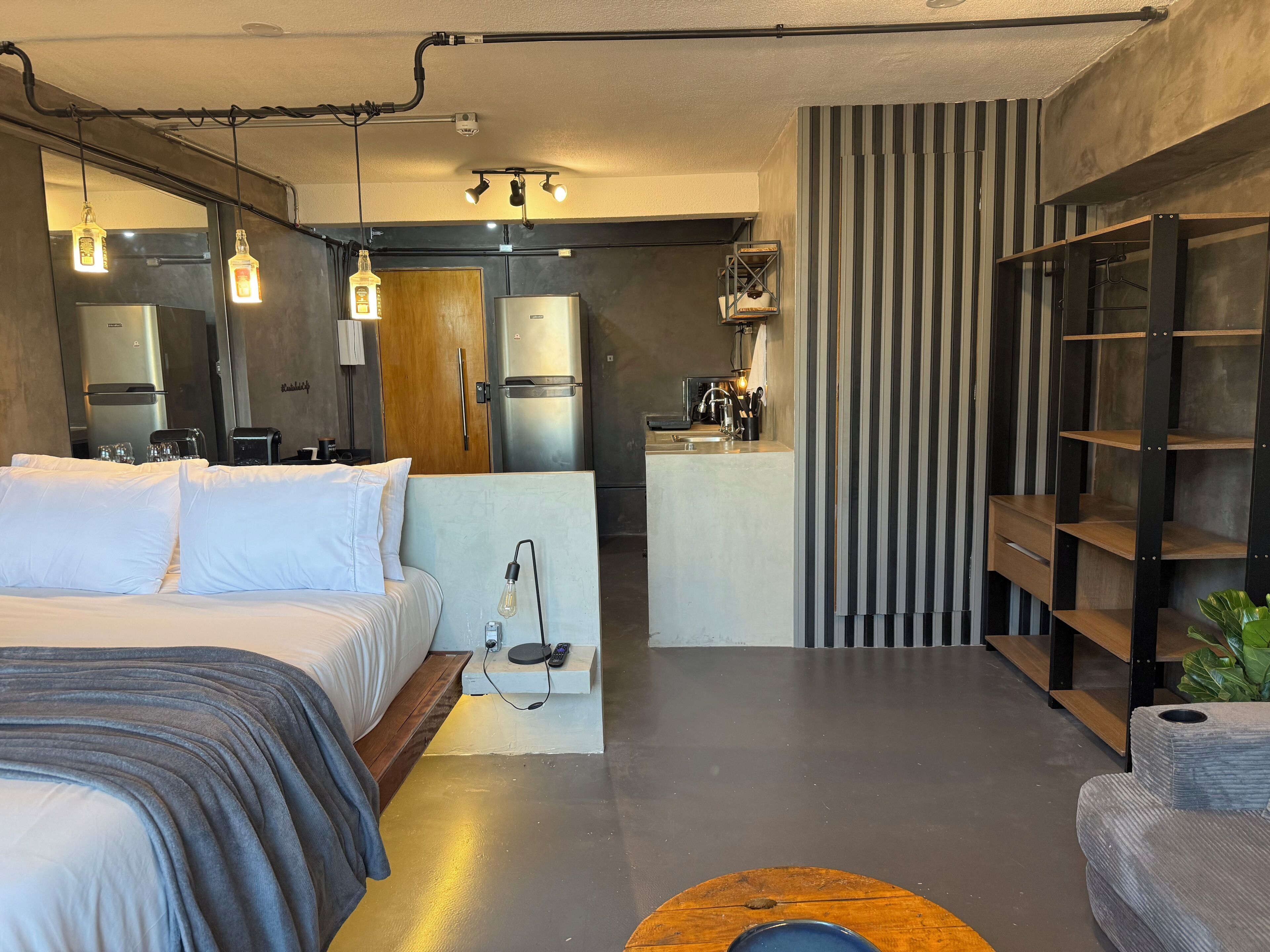 Ein modernes Hotelzimmer mit Bett, Küchenzeile und Barbereich.