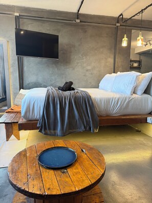 A modern room with a bed, a flat-screen TV, a round wooden table, and a bench. - Style & Comfort - SampaSky (São Paulo)