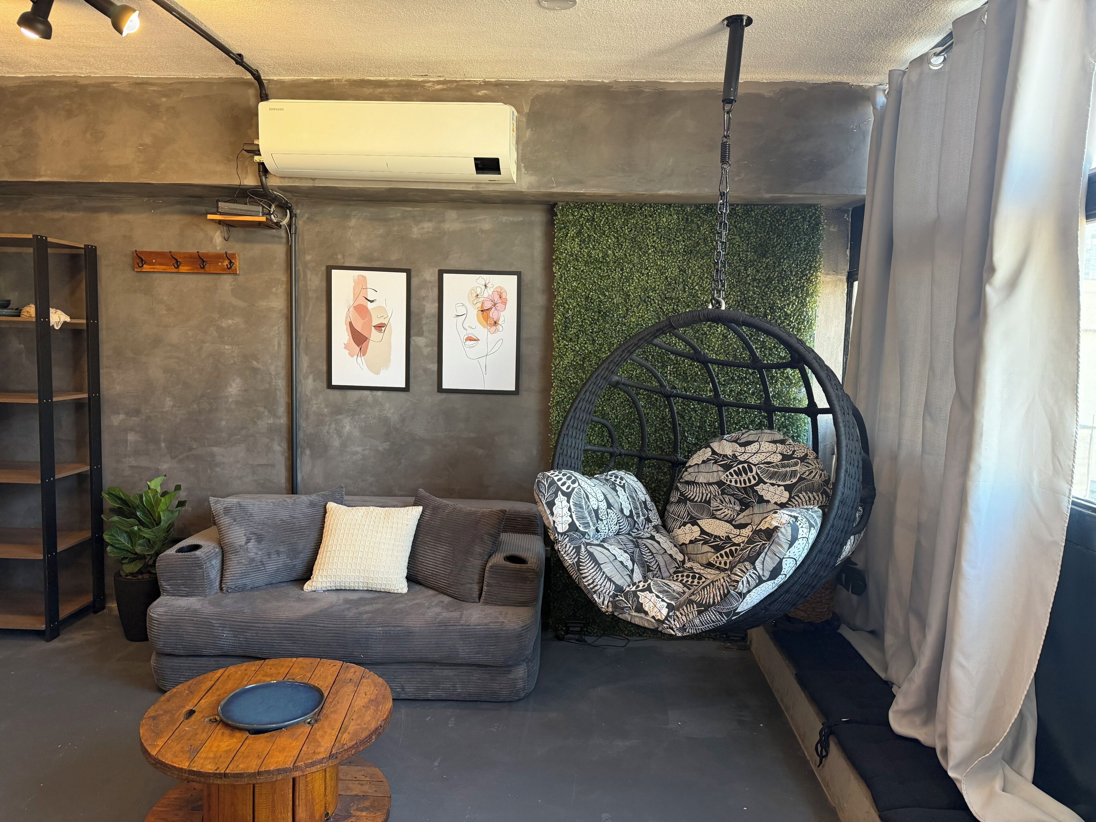 A modern living room with a hanging chair, a grey sofa, and a coffee table.