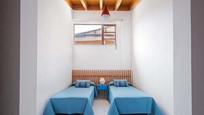 A small room with two beds, a wooden headboard, a window, and a red pendant light. - Casas Bioclimáticas Iter Noche y Dia (Granadilla de Abona)