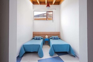 A small room with two beds, a wooden headboard, a window, and a red pendant light. - Casas Bioclimáticas Iter Noche y Dia (Granadilla de Abona)
