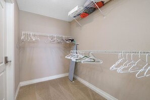 Ein begehbarer Kleiderschrank mit zwei weißen Metallregalen, eines mit aufgehängter Kleidung und das andere mit gefalteter Kleidung.