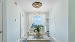 Un pasillo con candelabro, un sofá, una mesita de centro y vistas a edificios.