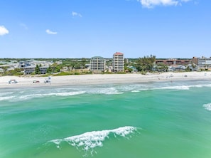 Blick auf die Küste mit Strand, Meer und Gebäuden im Hintergrund.