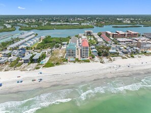 A coastal resort with beachfront villas, a marina, and a beach with umbrellas. - Luxury Beach Front at Fairwinds 402 (Indian Shores)