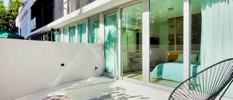 A modern building with large glass doors leading to a room with a bed and a chair.