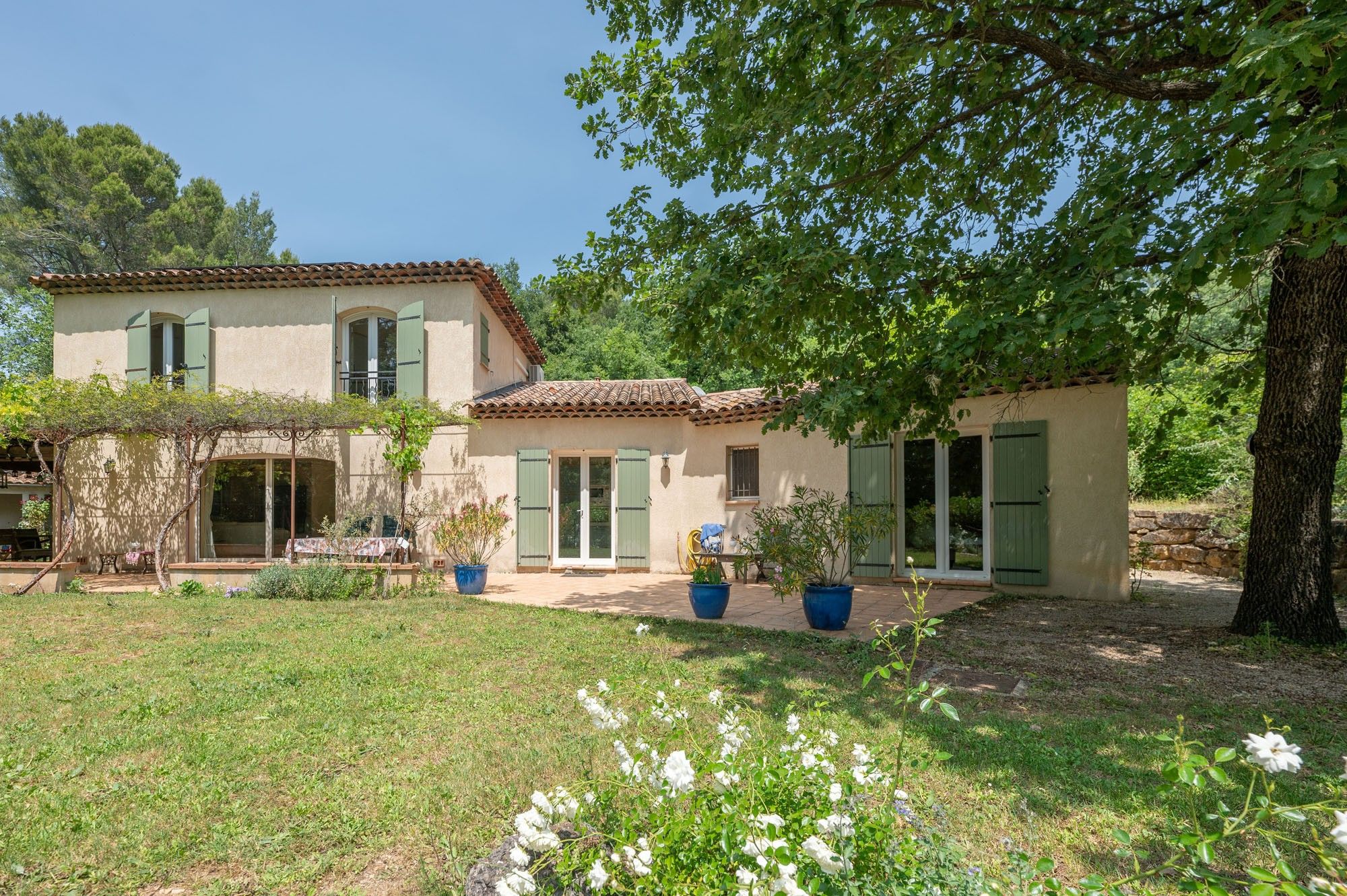 Une maison à deux étages avec un jardin, une pergola et un espace patio.