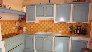 A kitchen with blue cabinets, a sink, and a coffee maker. - Holiday Home “Waterballet” with Pizza Oven, Wifi, and Air Conditioning (Villecroze)