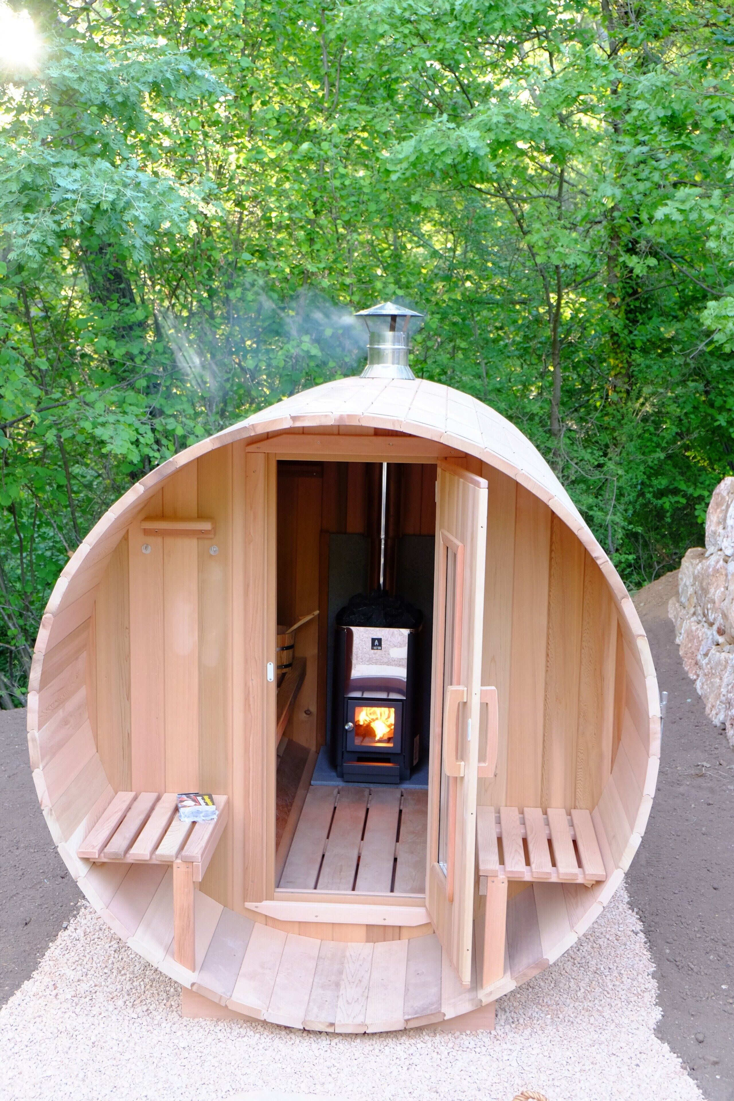 Une cabane en bois avec une cheminée, des bancs et une porte.