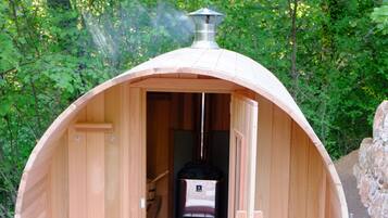 Une cabane en bois avec une cheminée, des bancs et une porte.