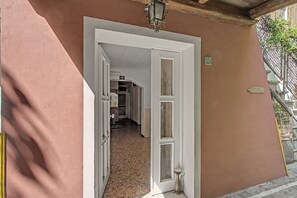 A hallway with a white door leading to a room, a small potted plant, and a sign on the wall. - Apartment 'Camera Giuly' with Shared Garden, Wi-Fi and Air Conditioning (Venice)