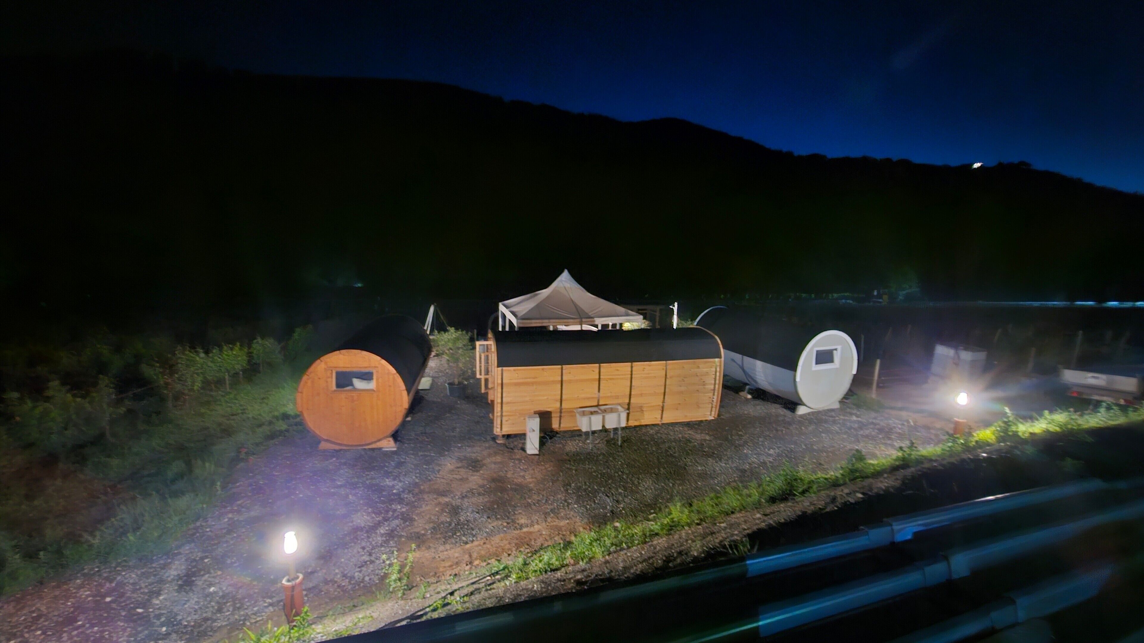 A cabin with a tent, a cylindrical structure, and a rectangular building with a sloped roof.