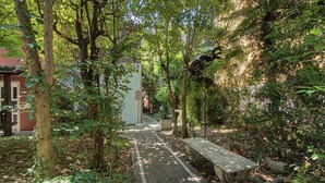 Un sendero serpentea por un jardín exuberante, con un banco y un accesorio de iluminación.