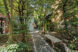 Ein Weg durch einen üppigen Garten mit einer Bank und einer Lampe.