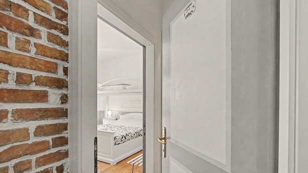 Una puerta que da a un dormitorio con cama, mesita de noche y lámpara.