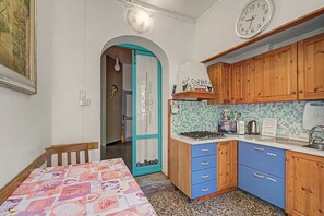 Eine kleine Küche mit Herd, Mikrowelle und einer Wanduhr.