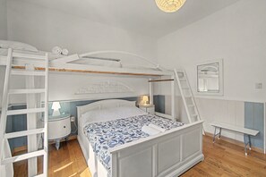 A bunk bed with a ladder, a bedside table with a lamp, and a mirror on the wall. - Gaia Room with Shared Garden, Wi-Fi and Air Conditioning (Venice)