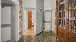 A hallway with a brick wall, a wooden door, and a cabinet with glass doors. - 'Camera Mini' Apartment with Shared Garden, Wi-Fi and Air Conditioning (Venice)