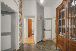 Ein Flur mit Backsteinwand, Holztür und Schrank mit Glastüren.