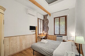 Une chambre à coucher avec un lit, un bureau, une chaise, une télévision et une fenêtre avec des rideaux.